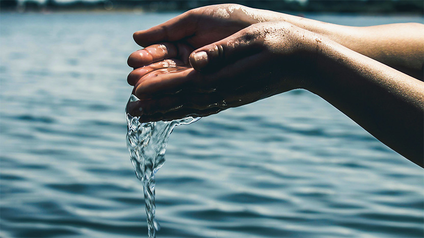 Mains jointes déversant de l'eau dans un fleuve