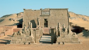 Temple égyptien antique en pierre situé dans le désert, orné de statues et bas-reliefs