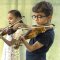 Two young children playing the violin