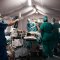 Équipe médicale en opération dans un bloc chirurgical sous tente, avec patient et équipements médicaux.