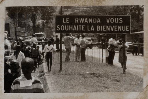 Black and white photograph with people in the street and "Rwanda welcomes you" sign (Photograph described in Convoy by Beata Umubyeyi Mairesse, Flammarion, 2024)
