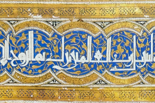 Bandeau décoratif en calligraphie arabe blanche sur fond bleu et or, ornée de motifs végétaux et encadrée de motifs géométriques dorés