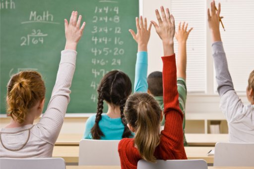 Des élèves levant la main dans une classe primaire