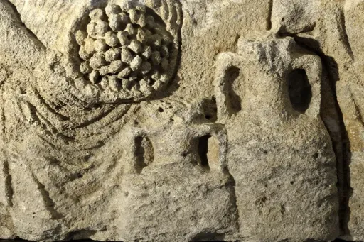 Sculpture en relief sur pierre représentant deux personnages, l'un tenant une grappe de raisin