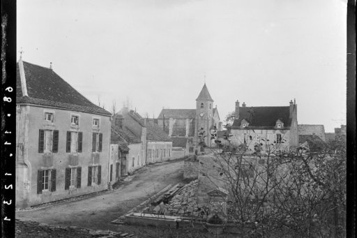 Vue ancienne d’un village avec église, maisons en pierre et fontaine centrale.