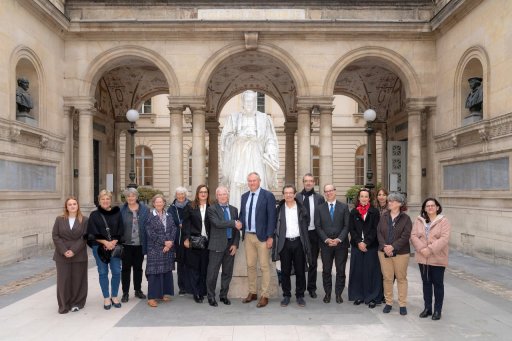 Groupe de personnes posant devant la statue Guillaume Budé du Collège de France