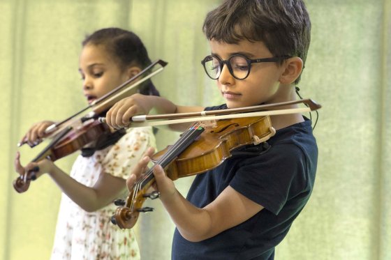 Two young children playing the violin