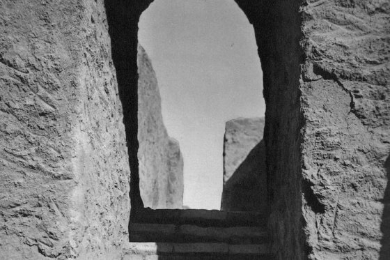Escalier en pierre menant vers une arche éclairée dans un mur de pierre ancienne