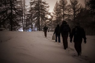 Groupe d'hommes marchant dans une forêt enneigée