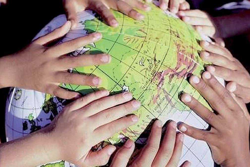 Gros plan sur des mains d'enfants posées sur un globe terrestre gonflable