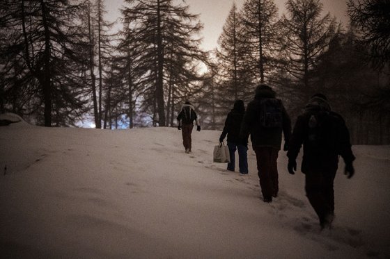 Groupe d'hommes marchant dans une forêt enneigée