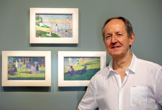 Prof. Pierre-Michel Menger in front of paintings by Georges Seurat