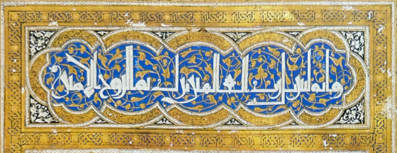 Bandeau décoratif en calligraphie arabe blanche sur fond bleu et or, ornée de motifs végétaux et encadrée de motifs géométriques dorés
