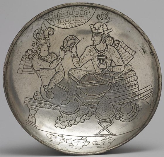 Plat ancien en métal gravé montrant deux personnages assis, tenant des objets rituels