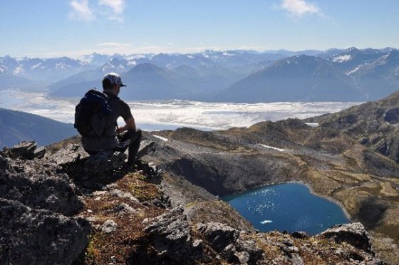 Un homme au sommet d'une montagne surplombant un lac