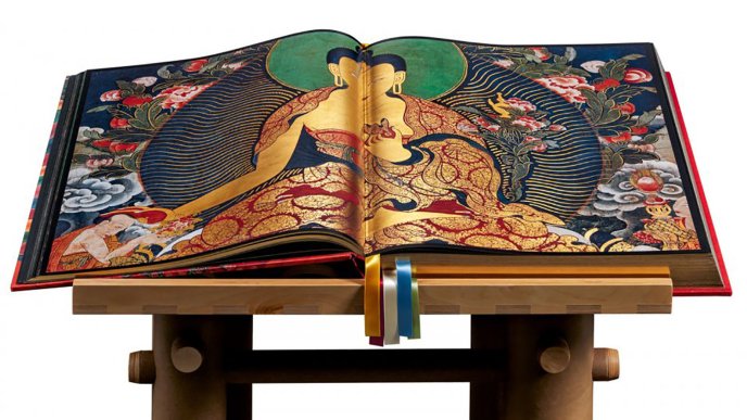 Thomas Laird's book, Murals of Tibet, opened on a lectern, presenting a Tibetan Buddhist illustration richly decorated with gilding and traditional motifs.
