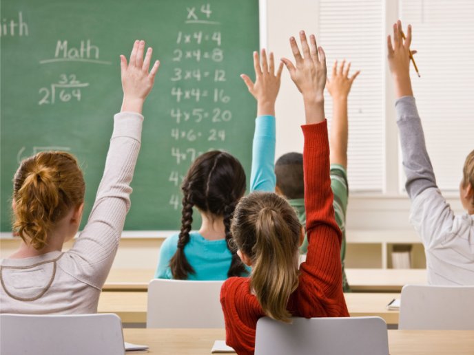 Des élèves levant la main dans une classe primaire
