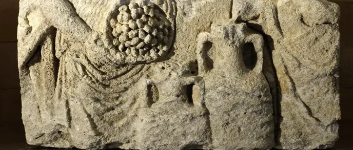 Sculpture en relief sur pierre représentant deux personnages, l'un tenant une grappe de raisin