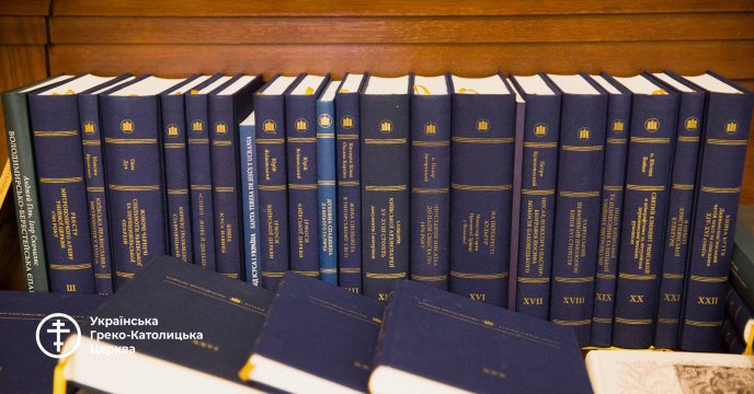 Étagère en bois sur laquelle sont rangés des livres à couverture rigide bleue avec des titres dorés, principalement en ukrainien