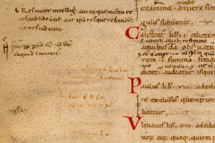 Fragment de manuscrit médiéval sur parchemin, écrit en latin à l’encre brune, avec de grandes lettres capitales rouges décorées en marge droite