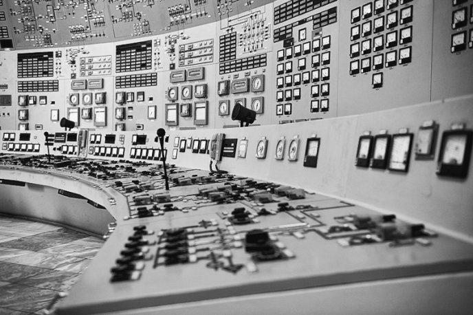 Display the full size picture: Salle de contrôle industrielle avec de nombreux panneaux de commande, cadrans, interrupteurs et instruments de mesure.