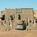 Temple égyptien antique en pierre situé dans le désert, orné de statues et bas-reliefs