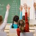 Des élèves levant la main dans une classe primaire