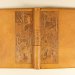 Livre ancien en cuir gravé avec motifs floraux et animaux, ouvert.